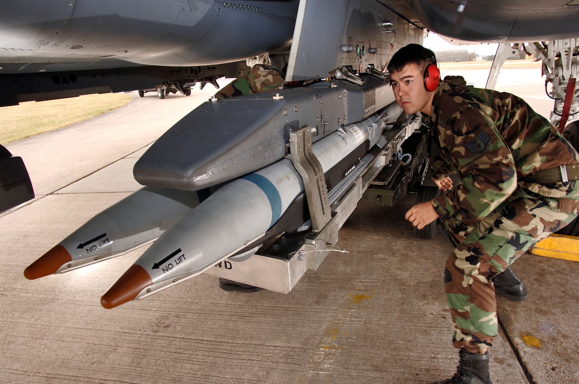 Staff Sgt. Randy Broome signals a jammer operator to move a Bomb Rack Unit 61 forward, while loading it onto an F-15E Strike Eagle at Royal Air Force Lakenheath, England, on Aug. 1. The NCO is an aircraft weapons specialist with the 48th Aircraft Maintenance Squadron. (U.S. Air Force photo/Master Sgt. Lance Cheung) 
