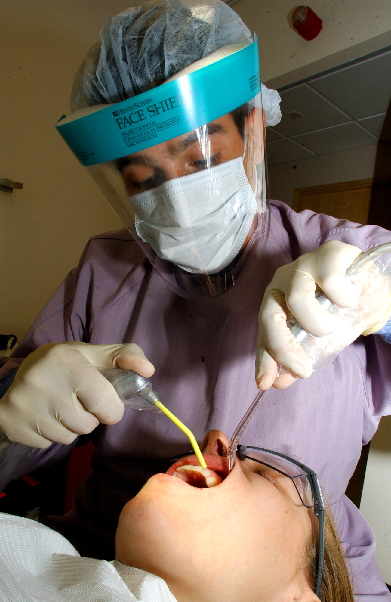 Tech. Sgt. Dennis Leon conducts a periodic oral exam on Senior Airman Lauryn Hashem at Royal Air Force Lakenheath, England, on July 31. The exam includes a cleaning, scaling, polishing, flossing, fluoride treatment and instruction on proper oral hygiene. Sergeant Leon is the the NCO in charge of preventive dentistry for the 48th Dental Squadron. Airman Hashem is an aircrew life support journeyman for the 492nd Fighter Wing. (U.S. Air Force photo/Senior Airman Kristi Emler) 
