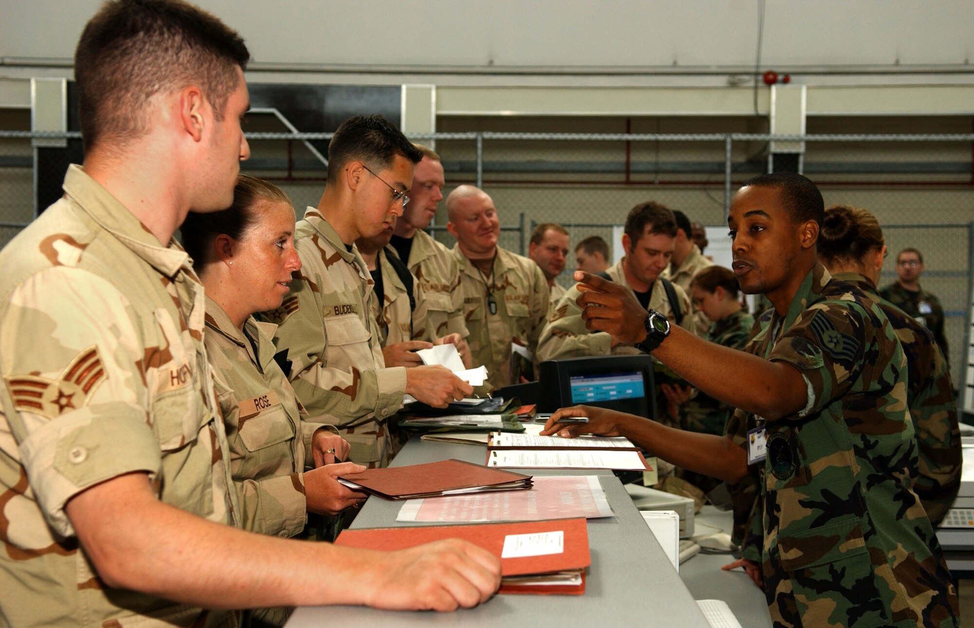 Staff Sgt. Donald Riley, 352nd Special Operations Squadron, right, verifies information in a mobility folder of another member of the 352nd SOG July 11. Military personnel flight representatives check folders to ensure identification cards, emergency records, dog tags and Air Force Form 245s are updated. The MPF has stations set up on the processing line to update administrative changes and dog tags. In a real world situation, a representative is on hand to escort deployable personnel back to MPF and update identification cards.  (U.S. Air Force photo by Staff Sgt. Tyrona Pearsall)