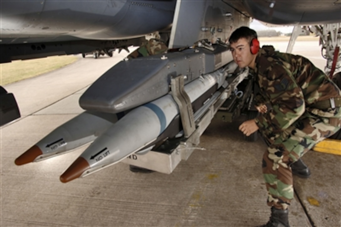 Staff Sgt. Randy Broome signals a jammer operator to move a BRU-61 bomb ...