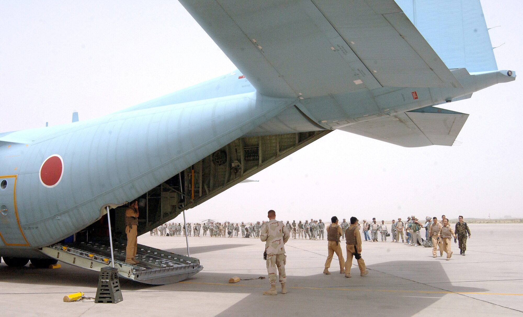 A Japan Air Self Defense Force C-130, painted blue for its affiliation with the United Nations, sits on the ramp at Sather Air Base, Iraq, as coalition servicemembers and civilians wait to board it July 31. This marked the first time a Japanese C-130 landed at Sather on Baghdad International Airport. The Japanese are now flying into Sather on a regular basis. (U.S. Air Force photo/Staff Sgt. Bryan Bouchard) 
