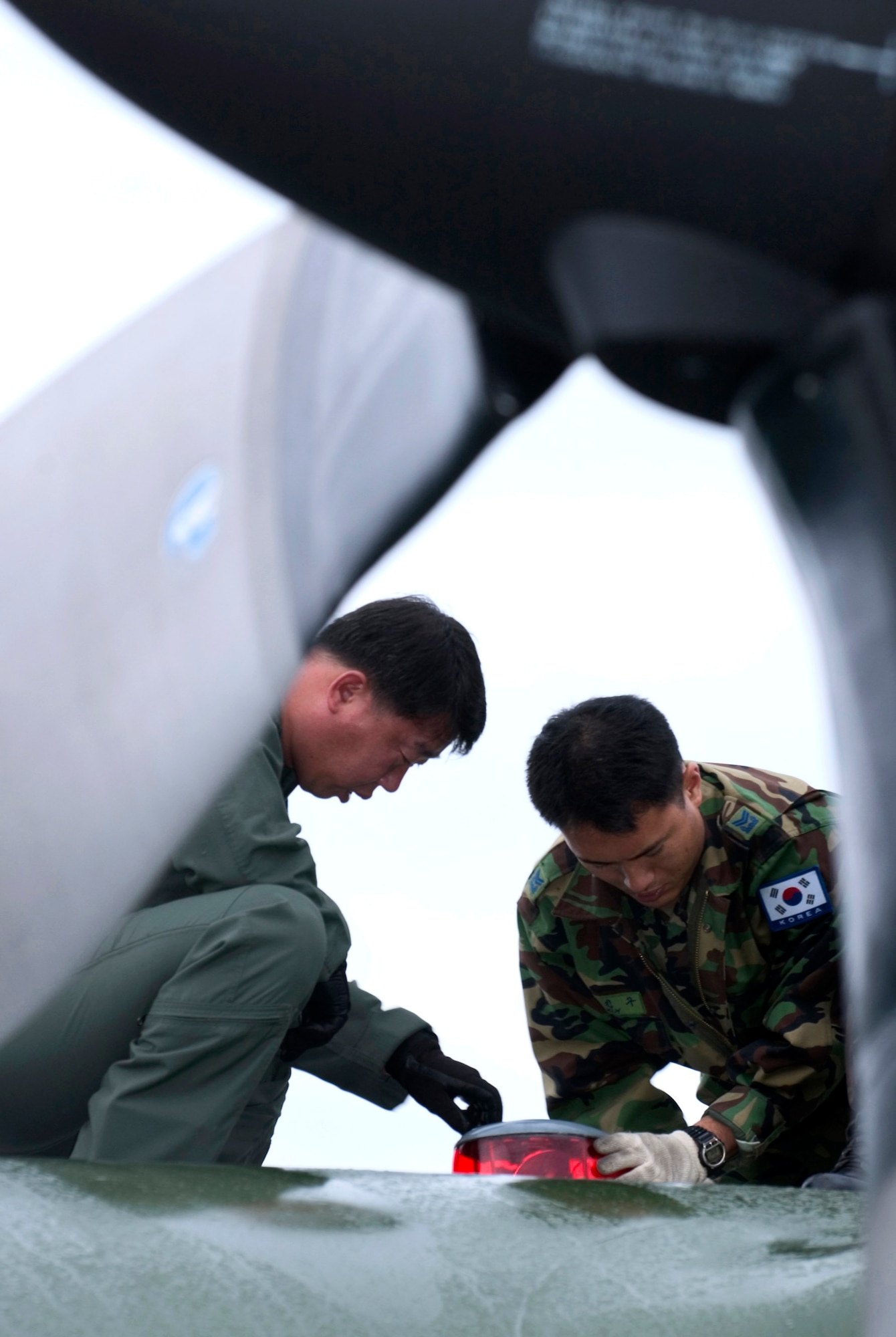 Chief Master Sgt. Jongkyu Lee and Master Sgt. Jinkoo Kim repair an anti-collision lamp on a C-130 Hercules at Elmendorf Air Force Base, Alaska, on July 25. They are members of the Korean air force and are participating in Cooperative Cope Thunder, a Pacific Air Forces exercise that ends Aug. 5. (U.S. Air Force photo/Senior Airman Garrett Hothan)