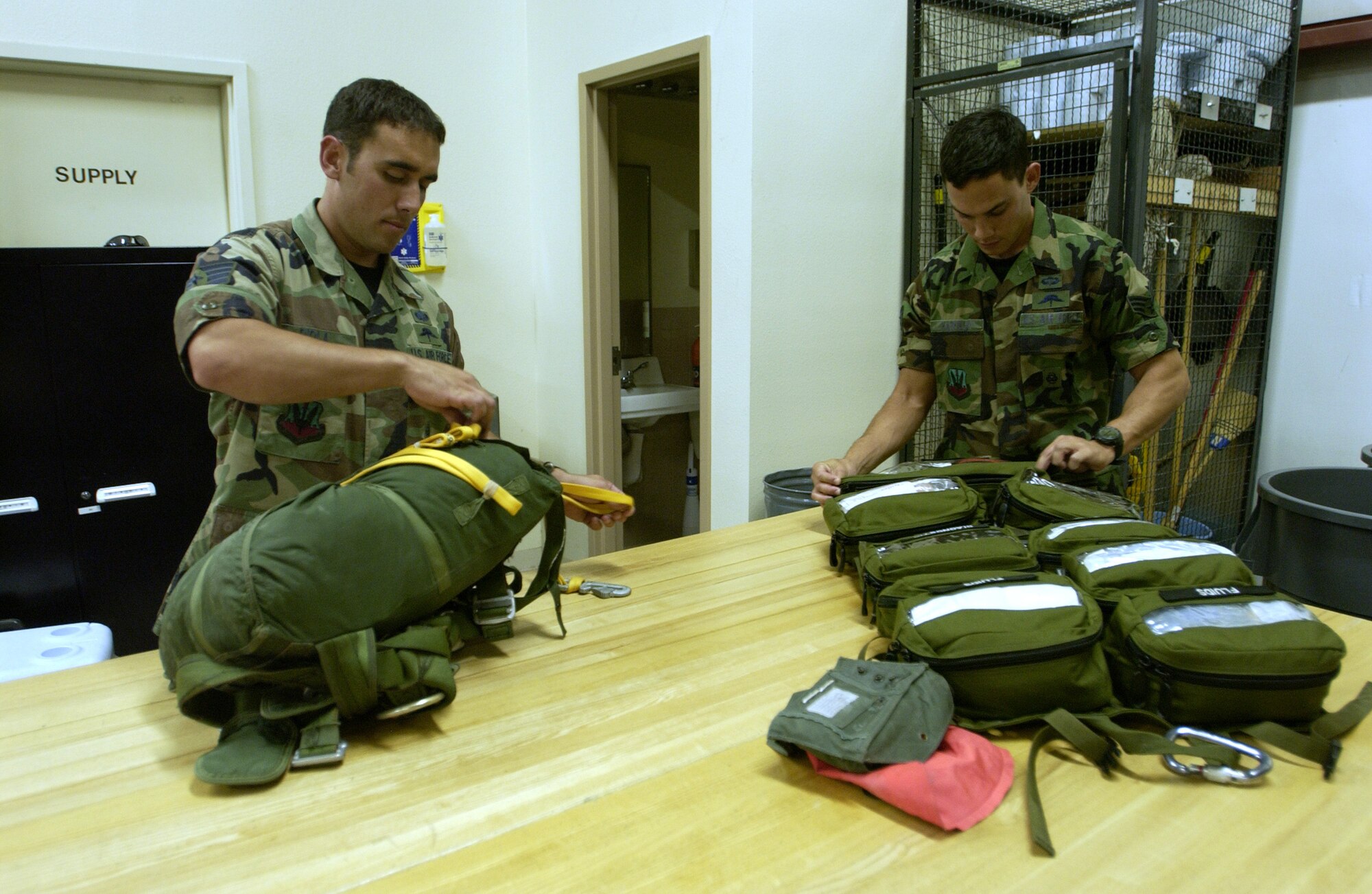 Staff Sgt. Jeremy Diola (left) checks his parachute, while Senior Airman Ryan Hatfield checks his medical bag. Both are members of the 58th Rescue Squadron at Nellis AFB. The two recently treated six people involved in a major automobile accident at Lake Mead, Nev. (Photo by Airman 1st Class Jason Huddleston)