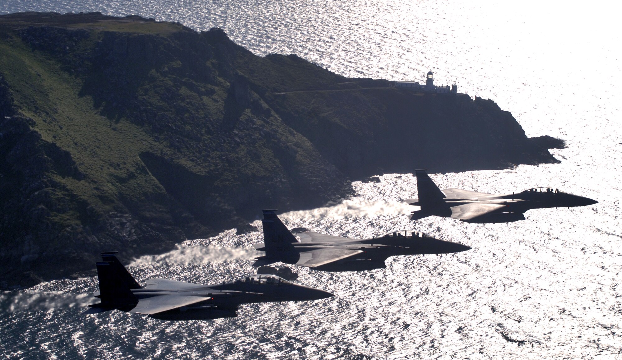 Three F-15E Strike Eagles from the 492nd Fighter Squadron at Royal Air Force Lakenheath, England, cruise at 300 mph along the southwestern English coast.  The aircrews were on the way to an area off the coast where they could practice basic surface attack techniques.  (U.S. Air Force photo/Master Sgt. Lance Cheung)