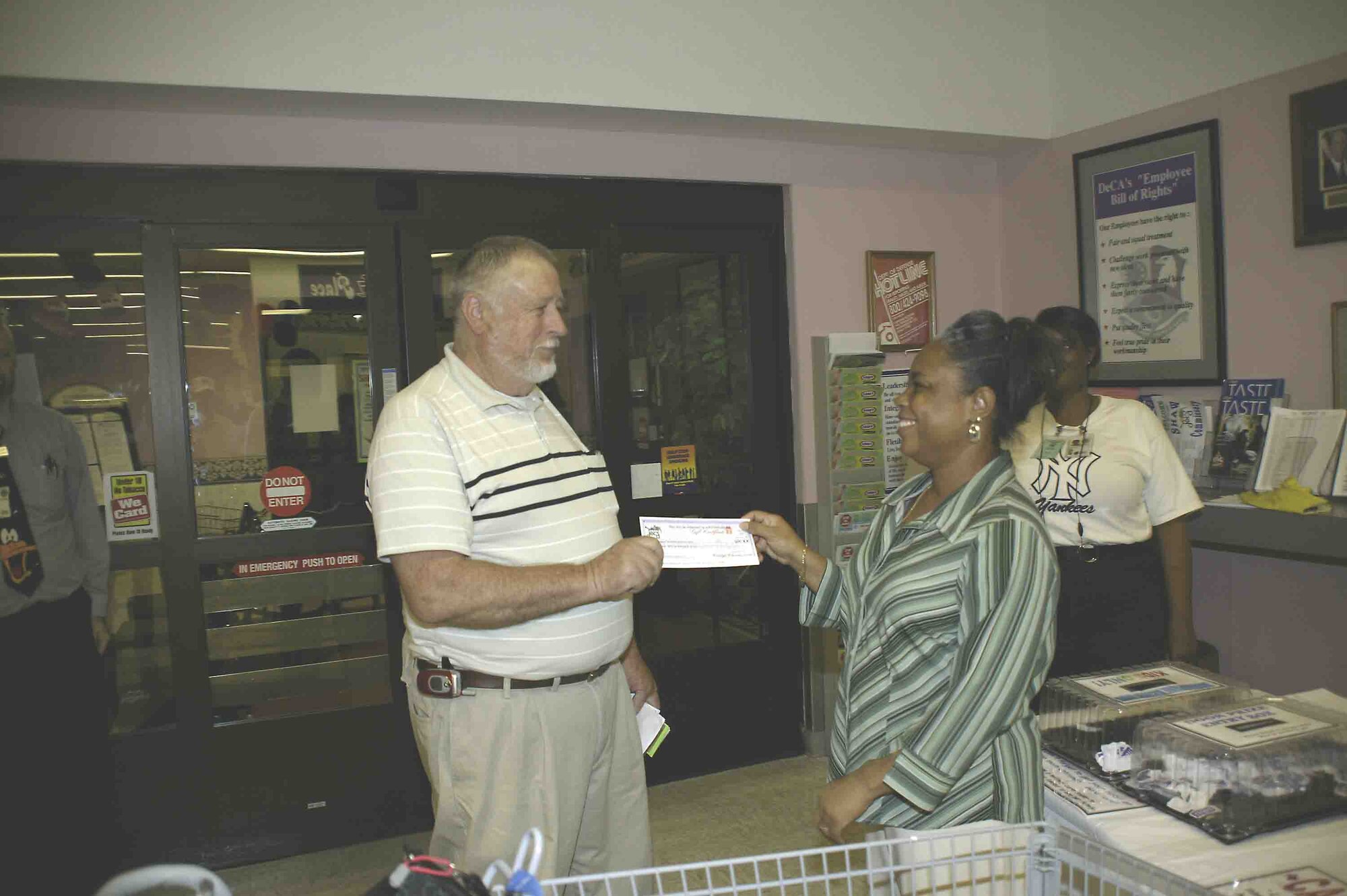 John Everett, Shaw Commissary vendor, presents a $25 gift certificate to Patricia Pettiford at the commissary Shop 'til You Drop event hosted by the Defense Commissary Agency July 27.  (U.S. Air Force photo/Kimberly Champagne)