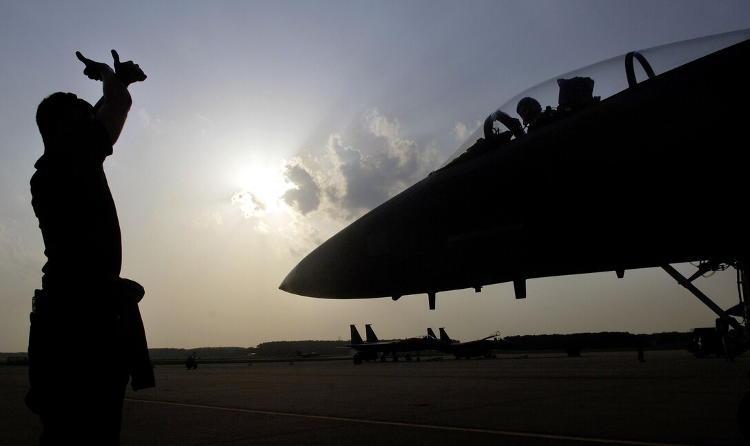 Senior Airman Ryan Rogers marshals in Capt. Matt Bruckner at Langley Air Force Base, Va., on July 28. The 27th, 71st and 94th Fighter Squadrons flew sorties and participated in exercises around the country while upgrades were done to their home runway. (U.S. Air Force photo/Staff Sgt. Samuel Rogers)
