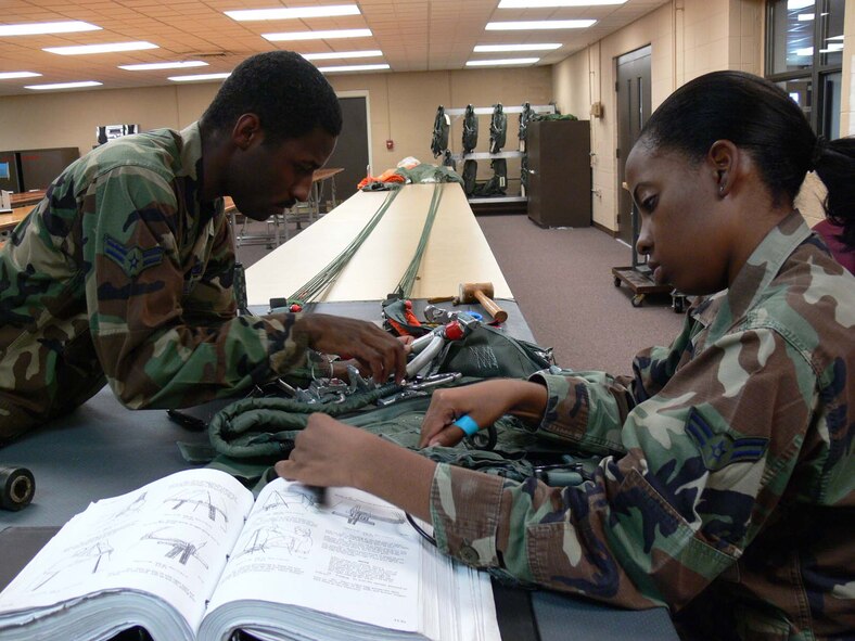 Airmen 1st Class Corey Smith and Brittney King, 347th Maintenance Squadron survival equipment apprentices, inspect and pack back automatic-style parachutes Tuesday. These parachutes, used by the HC-130P/N aircrew members and T-38 pilots, are repacked and inspected every six months. (Photo by Senior Airman Leticia Hopkins)