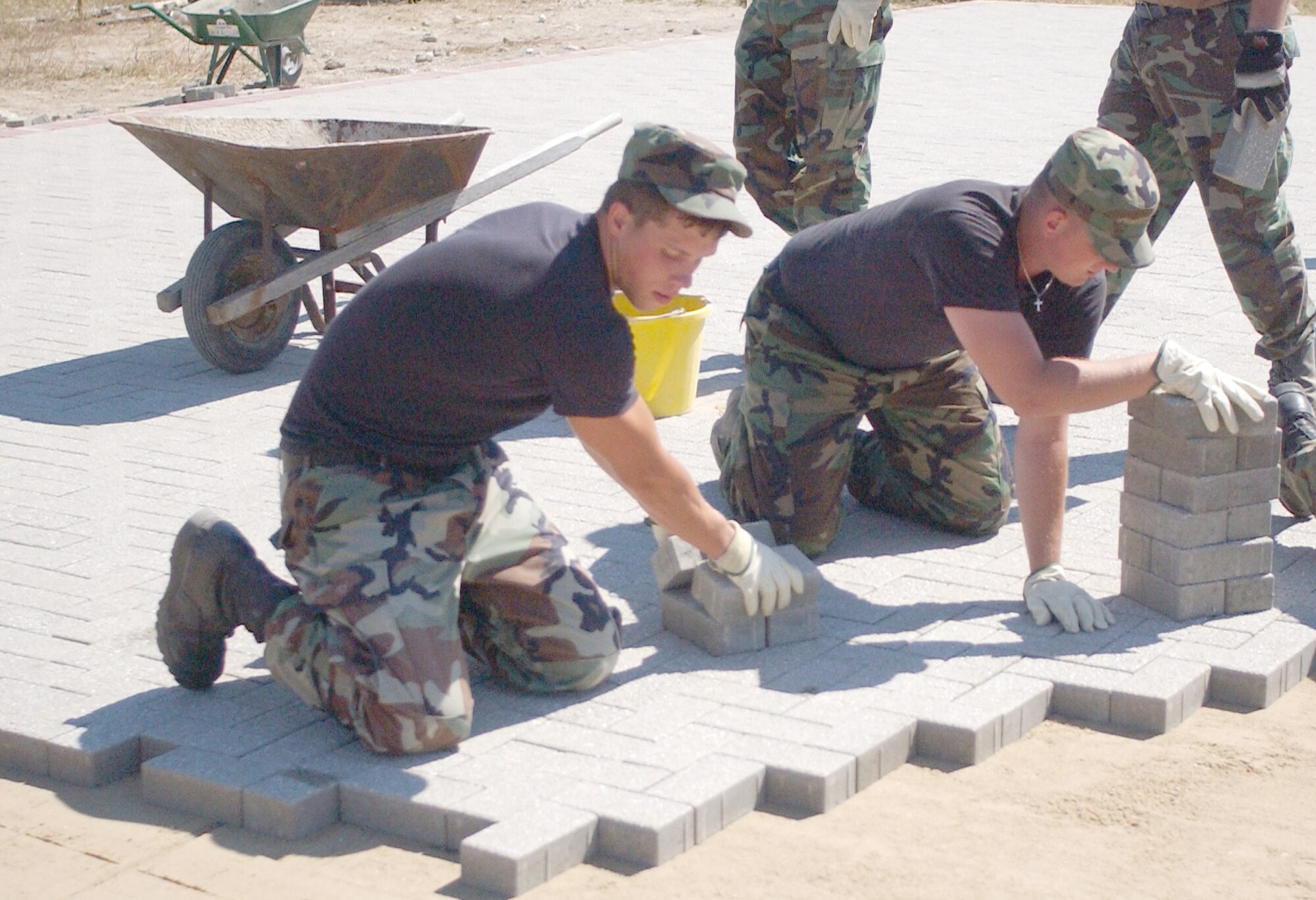 Senior Airman Jared LeMasters, and Senior Airman Zack Novotny, both of the 132nd Civil Engineer Squadron out of Des Moines, Iowa, lay a brick foundation at the site of a future sports facility which will be located behind the Hardstand Gym and Wellness Center. (U.S. Air Force photo by Michael Clements)