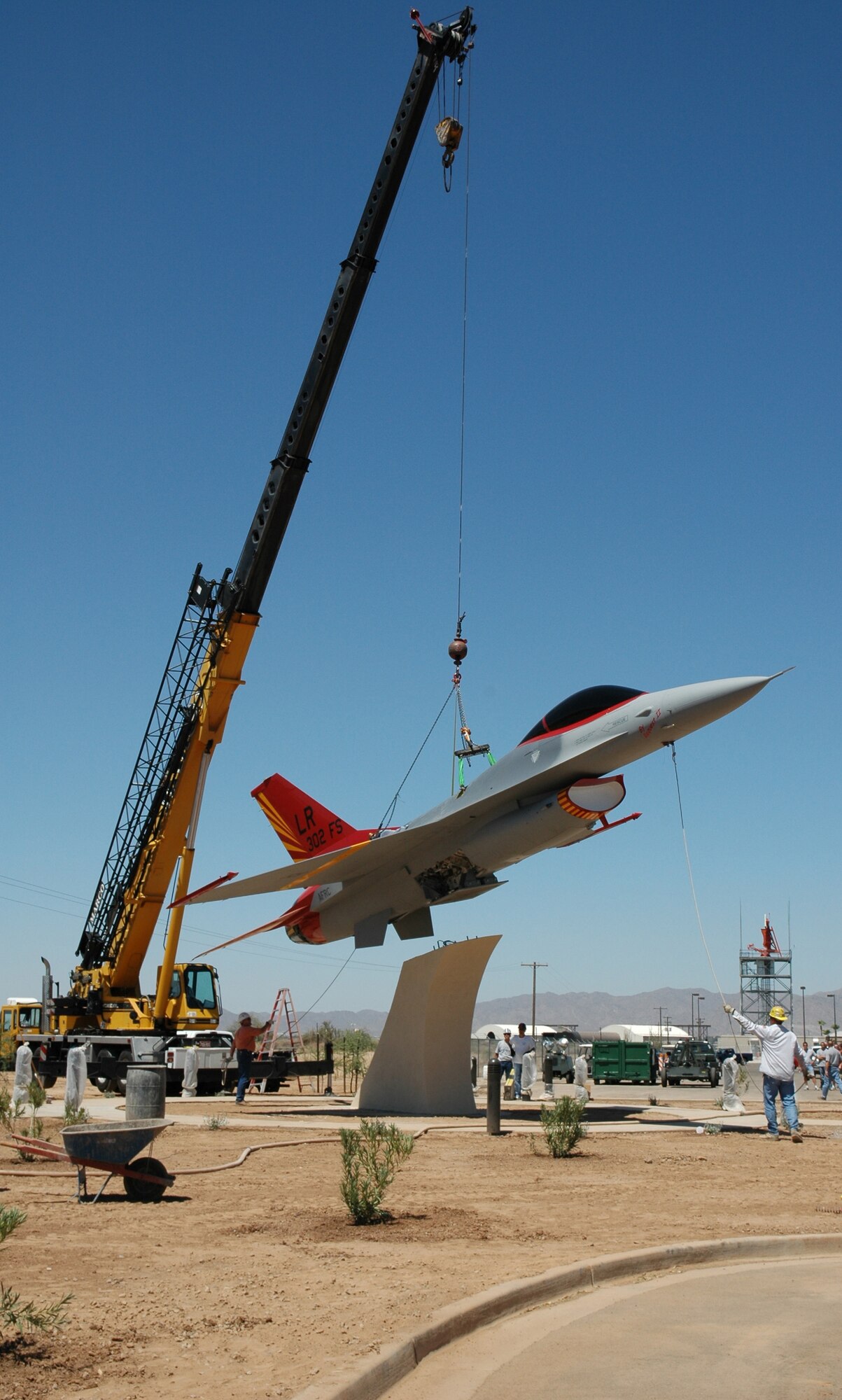 The F-16 Fighting Falcon painted with the Tuskegee Airmen's signature red tail is lowered into place July 11 in the Tuskegee Airmen Memorial Airpark in front of the 944th Fighter Wing at Luke Air Force Base, Ariz. The airpark serves as a reminder of the Tuskegee Airmen's contributions to America. (U.S. Air Force photo/Staff Sgt. Susan Stout)
