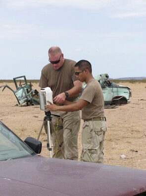 Senior Airman Luis Simpson, 944th Fighter Wing explosive ordnance disposal team member, and Airman 1st Class Adam Lozano, 56th Fighter Wing EOD team member, set up a disruptive device used to expose a vehicle and its contents. (U.S. Air Force photo/Teresa Walker)