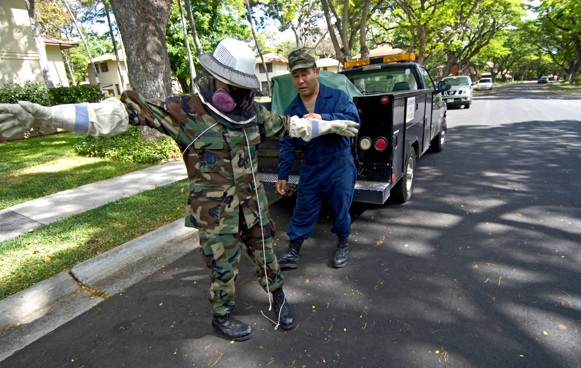 Tech. Sgt. Roy Takamoto checks Senior Airman Elizabeth Eggert for bees after she dusted a bee's nest in a housing area at Hickam Air Force Base, Hawaii, on Aug. 4. Sergeant Takamoto is with the Hawaii Air National Guard's 154th Wing and Airman Eggert is with the 15th Civil Engineer Squadron. Both Airmen are pest control specialists. (U.S. Air Force photo/Tech. Sgt. Shane A. Cuomo)