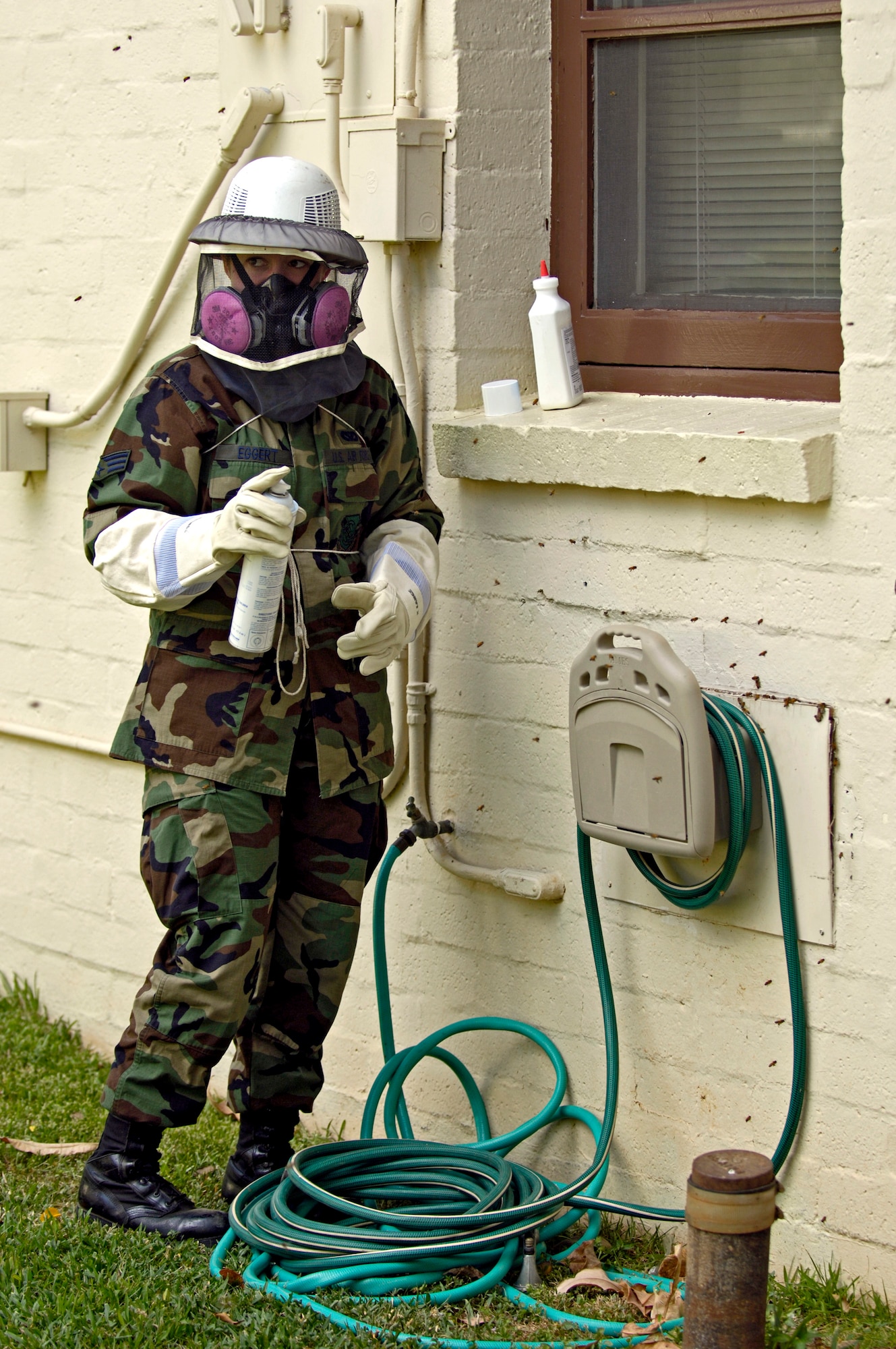 Senior Airman Elizabeth Eggert prepares to dust a bee's nest in a housing area at Hickam Air Force Base, Hawaii, on Aug. 4. Airman Eggert is with the 15th Civil Engineer Squadron pest control section. (U.S. Air Force photo/Tech. Sgt. Shane A. Cuomo) 
