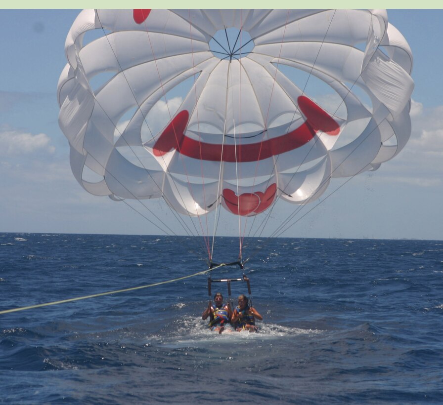 Tourists Joe Pippin and Lauren Poteet from Centerville, Md., take a dip in the water while parasailing Monday. In addition to choosing the height of their adventure, riders can also opt for a dry or a wet landing.