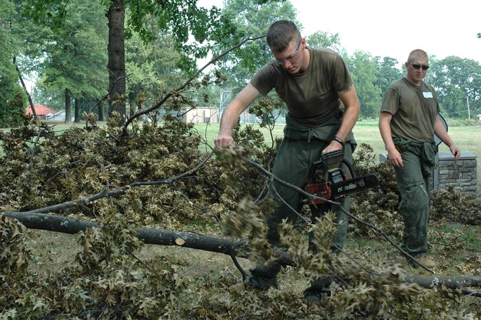 Lance Cpl. Ryan K. Varner of Defiance, Ohio, a water purification engineer with Chemical Biological Incident Response Force, II Marine Expeditionary Force, cuts away debris at St. Vincent Home for Children, as Pvt. Perry M. John of Buerne, Texas, drags it away Aug. 7. The home's grounds were damaged considerably during recent storms which slammed in to the St. Louis area the first week of August. The CBIRF Marines and sailors were in St. Louis supporting a large-scale civilian exercise, testing the county's first responders to disaster situations.