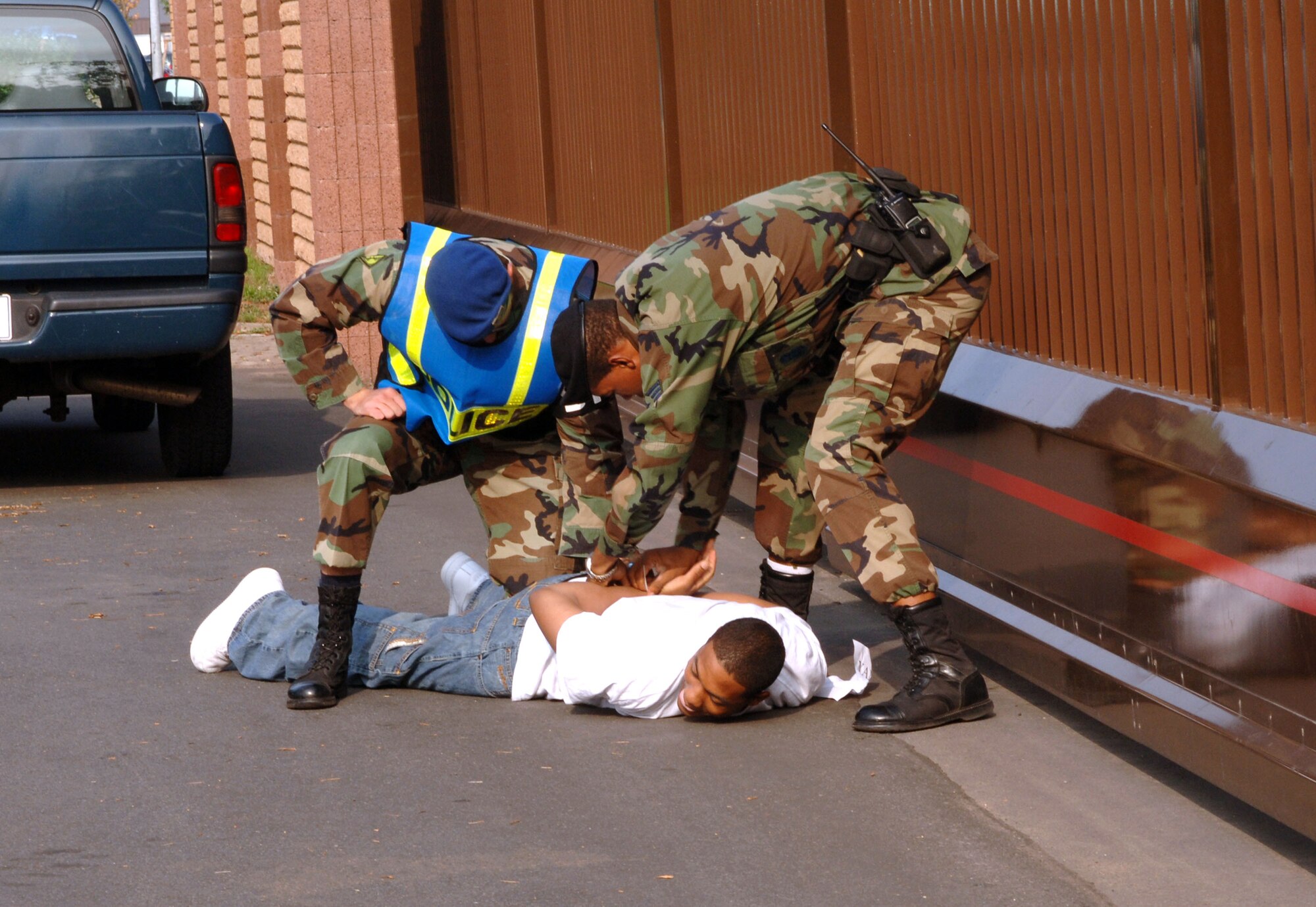 Airman Lamond Waller is cuffed on the ground by German Guard Sosha Dittert and Senior Airman Xavier Drake during a confrontation managment exercise at Vogelweh Air Station, Germany, on Aug. 4. The Airmen are with the 569th U.S. Forces Police Squadron. (U.S. Air Force photo/Airman 1st Class Julianne Trulson) 

