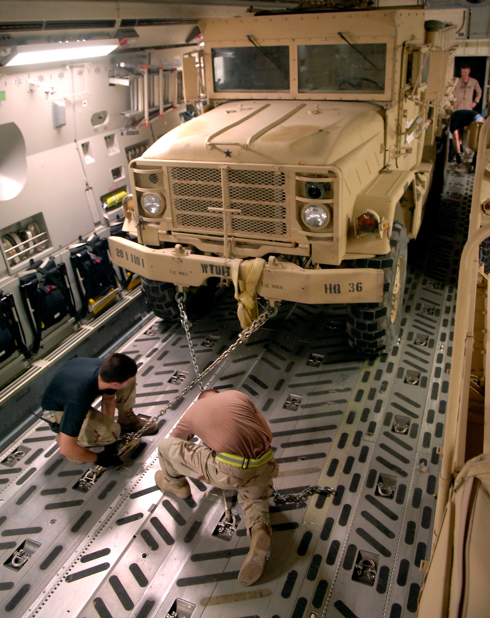 Airmen 1st Class James Kerr (right) and Spencer Stacey chain down a truck in a C-17 Globemaster III before takeoff from a forward operating location in Southwest Asia on Aug. 5. A C-17 from the 816th Expeditionary Airlift Squadron transported the vehicle to Afghanistan in support of Operation Enduring Freedom. Airman Kerr is with the 8th Expeditionary Aircraft Maintenance Squadron; Airman Stacey is with the 816th EAS. (U.S. Air Force photo/Senior Airman Brian Ferguson) 