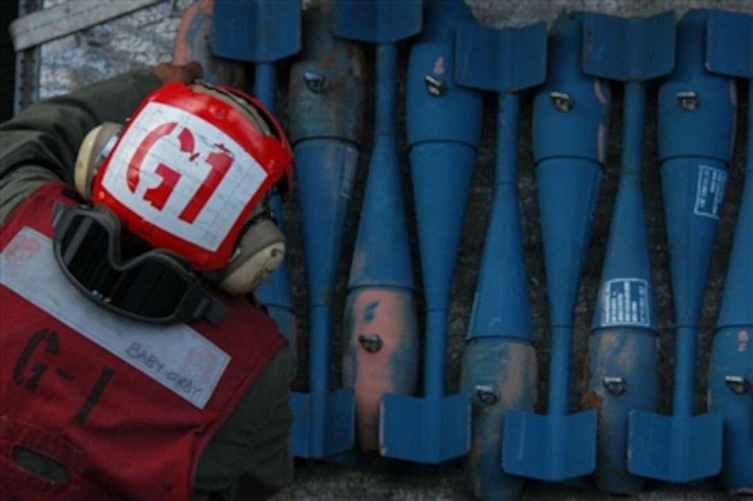 A U.S. Navy ordnanceman stacks blue MK-76 practice bombs onto a flatbed cart on the flight deck of USS Kitty Hawk (CV 63) as the ship operates in the Indian Ocean on Aug. 7, 2006.  