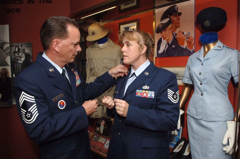 Chief Master Sgt. Malcolm McVicar explains the history of the circled U.S. lapel insignia to Tech. Sgt. Sharee Hileman at the Air Force Enlisted Heritage Research Institute at Maxwell-Gunter Air Force Base, Ala., on Aug. 8. A recent change to Air Force Instruction 36-2903 returned the circled insignia to the enlisted service dress uniform.  The origin of the insignia can be traced back to 1902. The current reauthorized insignia was worn by Airmen until the early 1990s when the lapel insignia was removed from both officer and enlisted uniforms.  Airmen can return to their heritage and begin wearing the circled insignia now, but must have it on by Jan. 1.  In addition, senior NCOs will no longer wear the shoulder board rank effective Oct. 1. Chief McVicar is director of the heritage institute, and Sergeant Hileman is the NCO in charge. (U.S. Air Force photo/Melanie E. Rodgers)
