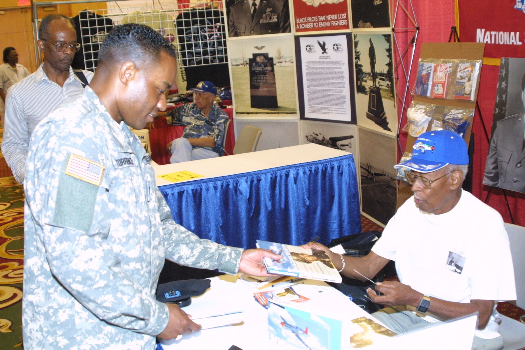 Retired Lt. Col. Alexander Jefferson hands an autographed copy of his book to Lt. Col. Gerald Torrence, Army War College, at the 35th Annual Tuskegee Airmen National Convention.


