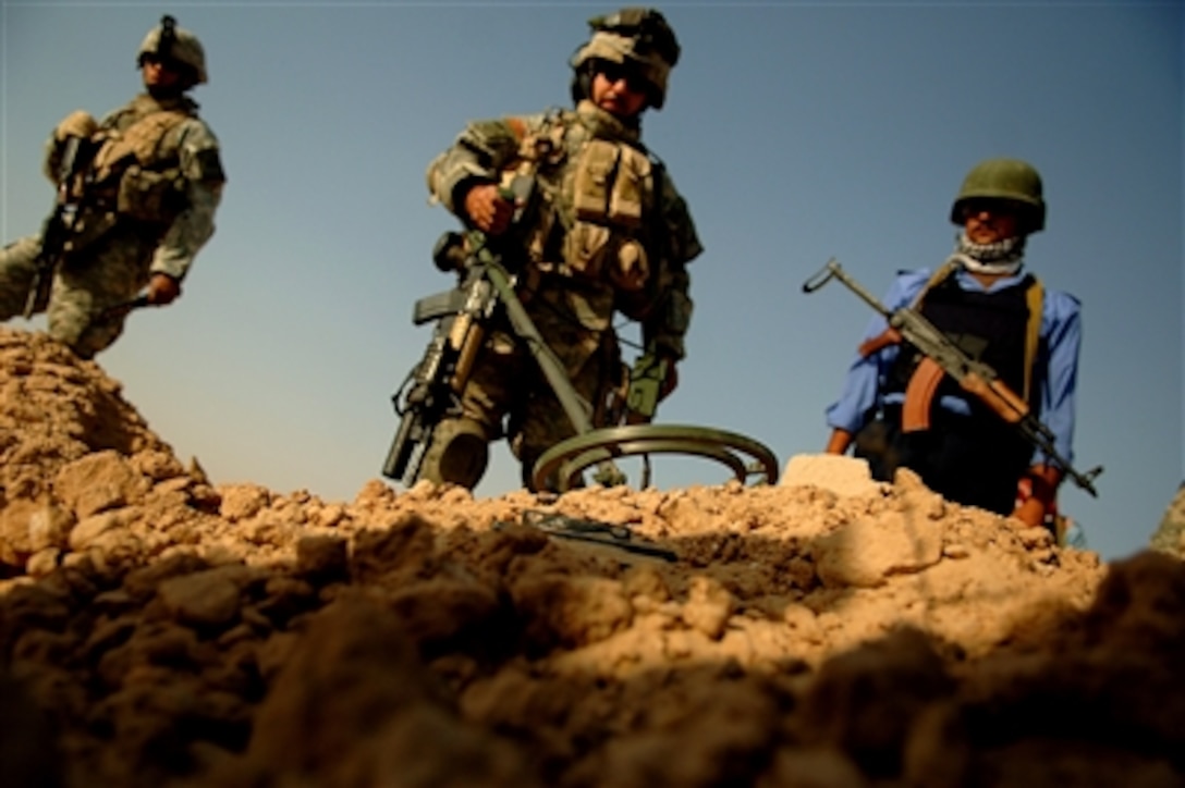 U.S. Army soldiers from 1st Platoon, Fox Troop, 1st Cavalry Regiment, 1st Armored Division, provide security and help Iraqi police search for weapons caches in a cemetery on the outskirts of Ramadi, Iraq, July 29, 2006.  