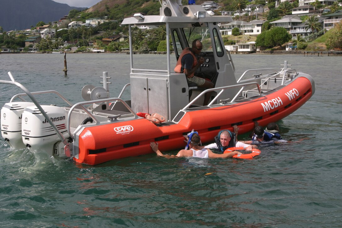 Petty Officer 2nd Class Jeremy Cosenza (left), diver, Waterfront Operations, pulls two crash victims to the side of the rescue boat during a search and rescue exercise Aug. 9, 2006. The exercise was a collabrotive effort between Waterfront Operations and the Federal Fire Department here.
