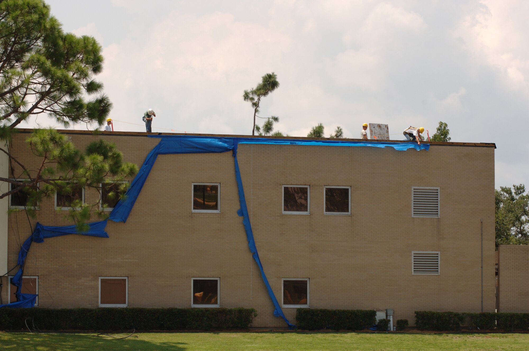Workers remove the last of the "blue roof" from the 403rd Wing Headquarters building. The building was heavily damaged during Hurricane Katrina last year. Damages to wing facilities totaled more than $40 million, with rebuilding and repairs still ongoing nearly a year later. The wing's command section and headquarters staff are located in temporary trailers and many other offices from other affected buildings have been relocated to temporary office spaces.