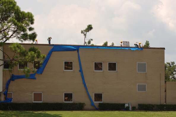 Workers remove the last of the "blue roof" from the 403rd Wing Headquarters building. The building was heavily damaged during Hurricane Katrina last year. Damages to wing facilities totaled more than $40 million, with rebuilding and repairs still ongoing nearly a year later. The wing's command section and headquarters staff are located in temporary trailers and many other offices from other affected buildings have been relocated to temporary office spaces.
