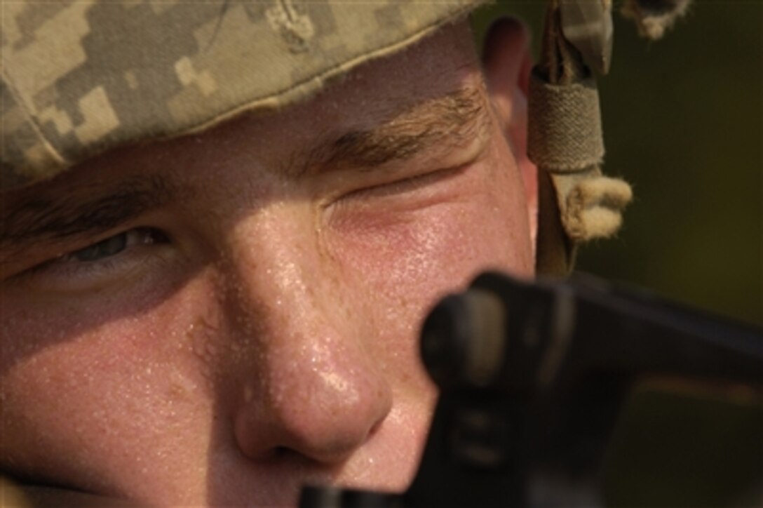 A U.S. Army private looks down the sights of his weapon as he competes in a buddy movement course during basic combat training on Fort Jackson, S.C., on Aug. 9, 2006.  The training is nine-weeks in length and is divided into red, white and blue phases.