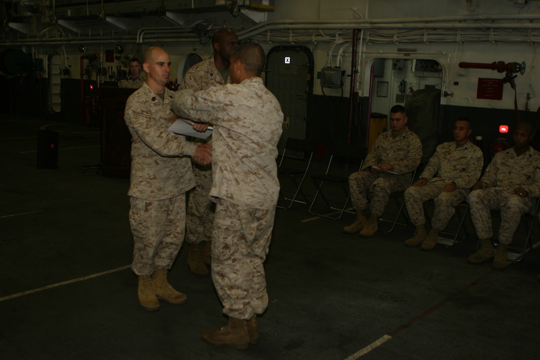 First Sgt. Vernon E. Derby, Company First Sgt., India Battery, Battalion Landing Team 2/5, 15th Marine Expeditionary Unit, congratulates a Marine with the 15th MEU during the graduation ceremony of Corporals Course 1-09 in the hangar bay aboard USS Peleliu (LHA 5).::r::::n::   Corporals from all elements of the 15th MEU, including the Command Element, Battalion Landing Team 2/5, Combat Logistics Battalion-15 and Marine Medium Helicopter Squadron-165 (REIN), graduated from Corporals Course Oct. 1. ::r::::n::   Col. B.D. Beaudreault, the guest speaker during the ceremony, reminded the graduating Marines of past generations of Noncommissioned Officers in the Marine Corps, specifically the Marines of the Battalion Landing Team 2/5, whose forbears  in the 5th Marine Regiment fought during the invasion of Peleliu in WWII, the battle for which the USS Peleliu (LHA 5) is named.::r::::n::   Corporals Course is a period of instruction designed to solidify the leadership of junior Marine NCOs to better serve Marines in their charge.::r::::n::   The Camp Pendleton, Calif. based 15th MEU is comprised of approximately 2,200 Marines and Sailors and is a forward deployed force of readiness capable of conducting numerous operations, such as Non-Combatant Evacuation Operations, Humanitarian Assistance Operations and a wide range of amphibious missions. ::r::::n::   The 15th MEU is currently deployed aboard the USS PELELIU (LHA-5), USS DUBUQUE (LPD-8) and USS PEARL HARBOR (LSD-52). (Official U.S. Marine Corps photo by Cpl. Timothy T. Parish)(RELEASED)::r::::n::