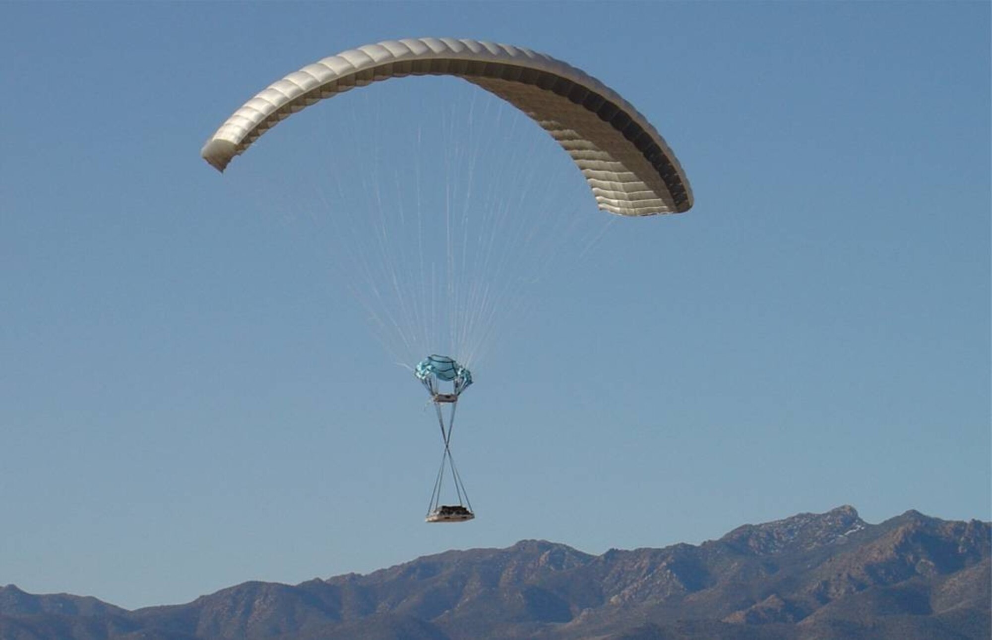 YUMA PROVING GROUNDS, Ariz. (AFMCNS) — A 10,000-pound payload dropped from a C-130 at 25,000 feet over Yuma Proving Grounds, Arizona, is guided by the Joint Precision Airdrop System. JPADS provides safe/accurate high altitude delivery to ground troops, while also protecting the aircraft, aircrew and the supplies. JPADS has a steerable canopy, an electro-mechanical steering actuator with an airborne guidance unit. The mobility community is calling JPADS the JDAM (Joint Direct Attack Munition) for logistics, because both are GPS-guided systems. JPADS delivers supplies and JDAM delivers guided munitions attacks. (Air Force courtesy photo)