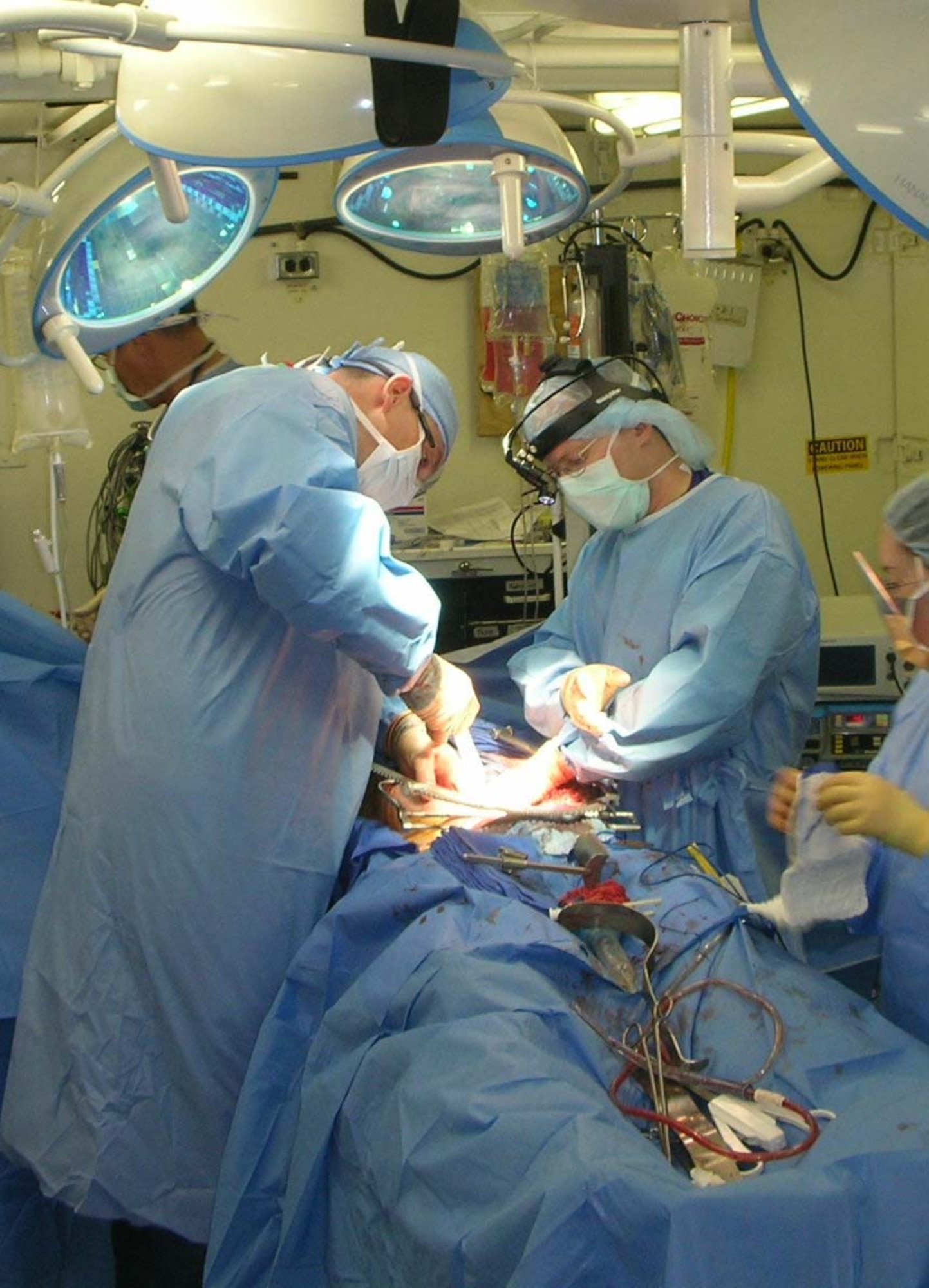 BALAD AIR BASE, Iraq -- Surgeon of the day, Maj. (Dr.) Steve Barnes (left) works with vascular surgeon Maj. (Dr.) Cabot Murdock to remove shrapnel from a U.S. Army Soldier at the Air Force Theater Hospital here, Aug. 7.  Severely wounded by a roadside bomb, the Soldier's life hung in the balance until the surgeons found and extracted fragments of metal and bone from the Soldier's iliac veins deep in his pelvis. After removing a jagged shard of metal the size of a quarter, Major Barnes said the Soldier was "going to be alright." During a 24-hour shift, the surgeon of the day treated 18 patients and performed nine operations.  Though the surgical staff is equipped to handle any injury just short of doing heart transplants, the most common trauma injuries they see are from improvised explosive devices.  (U.S. Air Force photo by Lt. Col. Bob Thompson)               