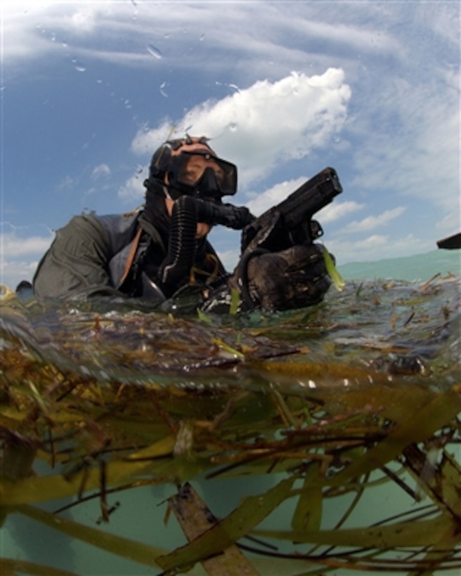 A U.S. Navy SEAL surfaces with his weapon drawn during a combat swimmer training dive on May 18, 2006.