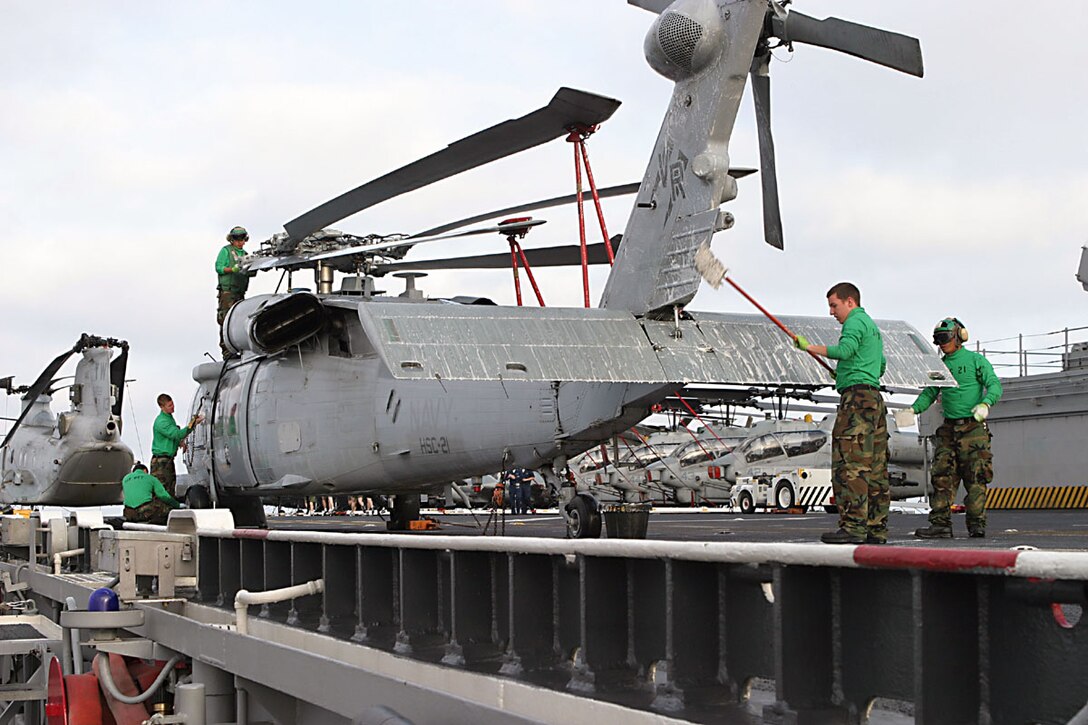 ABOARD USS BOXER (Aug. 11, 2006) -- Navy sailors with Search and Rescue Detachment wash down a Seahawk Navy helicopter on the flight deck. "Wash jobs" must be performed every seven days to help clean off salt and prevent corrosion. Expeditionary Strike Group 5 and the 15th Marine Expeditionary Unit is preparing for the Joint Task Force Exercise which is the final evaluation before their deployment through the Western Pacific. (Official USMC photo by Cpl. Thomas J. Grove) (Released)