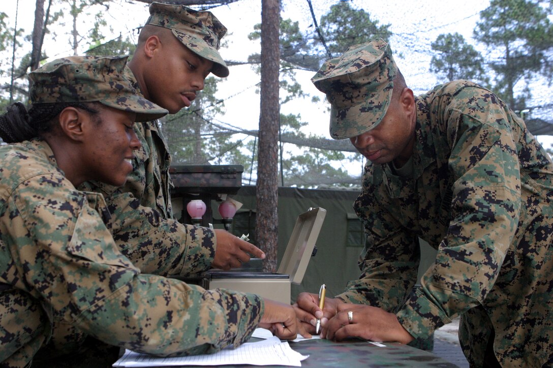MARINE CORPS BASE CAMP LEJEUNE, N.C. (Aug. 14, 2006) - Gunnery Sgt. Gregory Moore of Philadelphia, staff noncommissioned officer-in-charge for Food Service Company, Headquarters Battalion, Combat Logistics Regiment 27, 2nd Marine Logistics Group, pays for his meal at the field dining facility at Training Zone Owl, Aug. 14. Corporal Leah Cayo of Philadelphia (left), a food service specialist, and Lance Cpl. Tamall M. Spurlock of Wilmington, Del., check people into the dining facility which was built in preparation for the Maj. Gen. W. P. T. Hill Memorial Award for Food Service Excellence.
