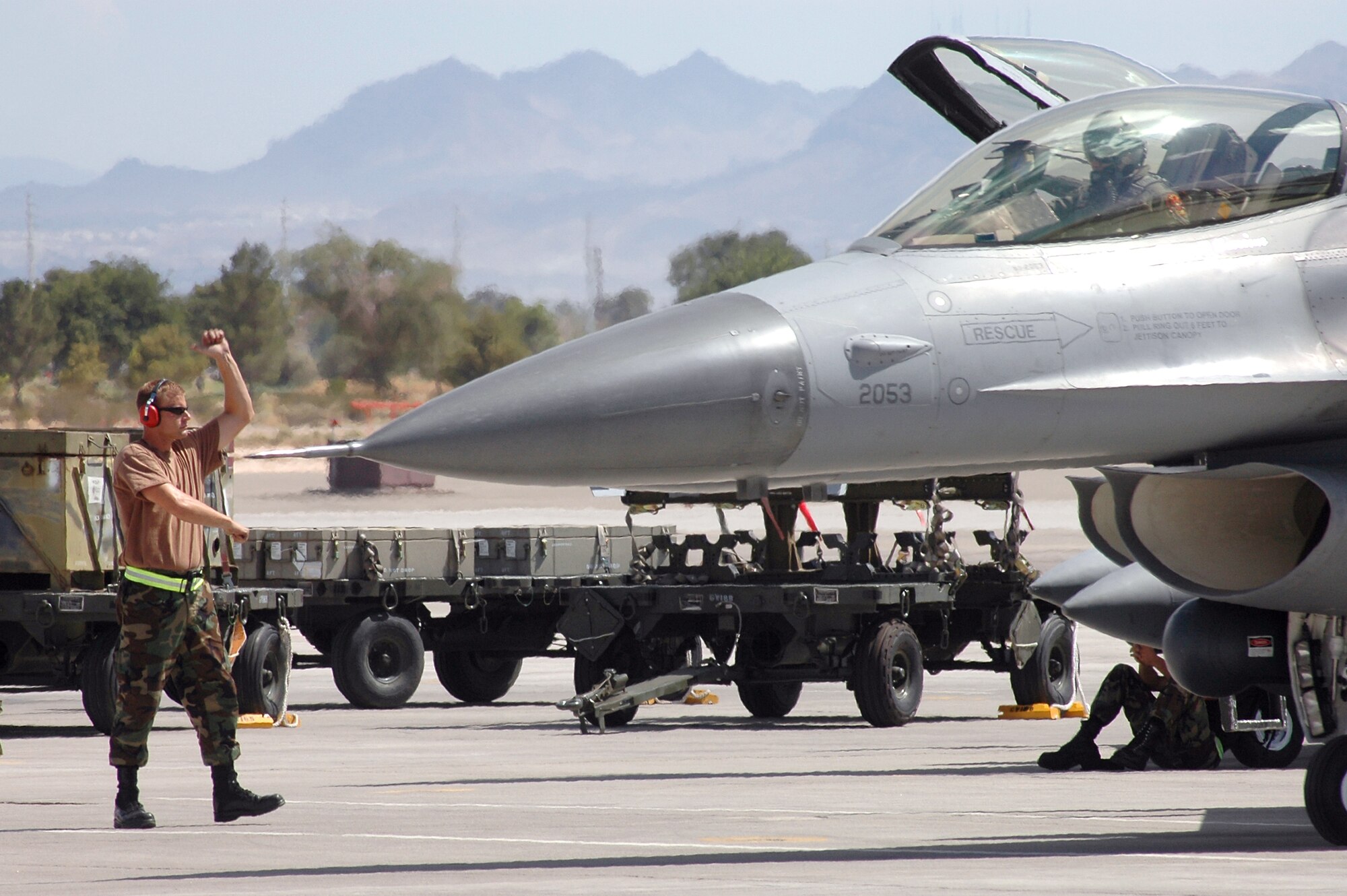 Senior Airman Brent Bott marshals an F-16 Fighting Falcon for a mission at Red Flag 06-02 at Nellis Air Force Base, Nev., on Aug. 8.  Airman Bott is a crew chief with the Iowa Air National Guard's 132nd Fighter Wing in Des Moines.  (U.S. Air Force photo/Tech.Sgt. Bob Sommer)