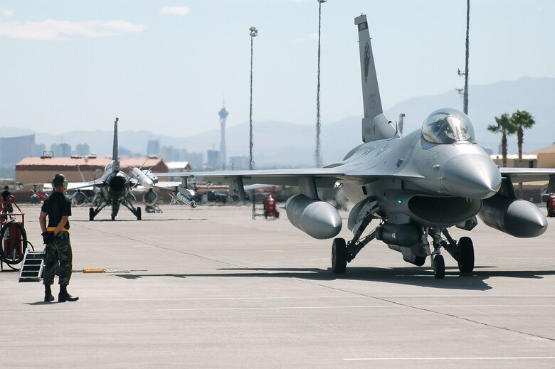Senior Airman Ryan Stott prepares to marshal an F-16 Fighting Falcon that is ready for a mission at Red Flag 06-02 at Nellis Air Force Base, Nev., on Aug. 8.  Airman Stott is a crew chief with the Iowa Air National Guard's 132nd Fighter Wing in Des Moines.  (U.S. Air Force photo/Tech.Sgt. Bob Sommer)