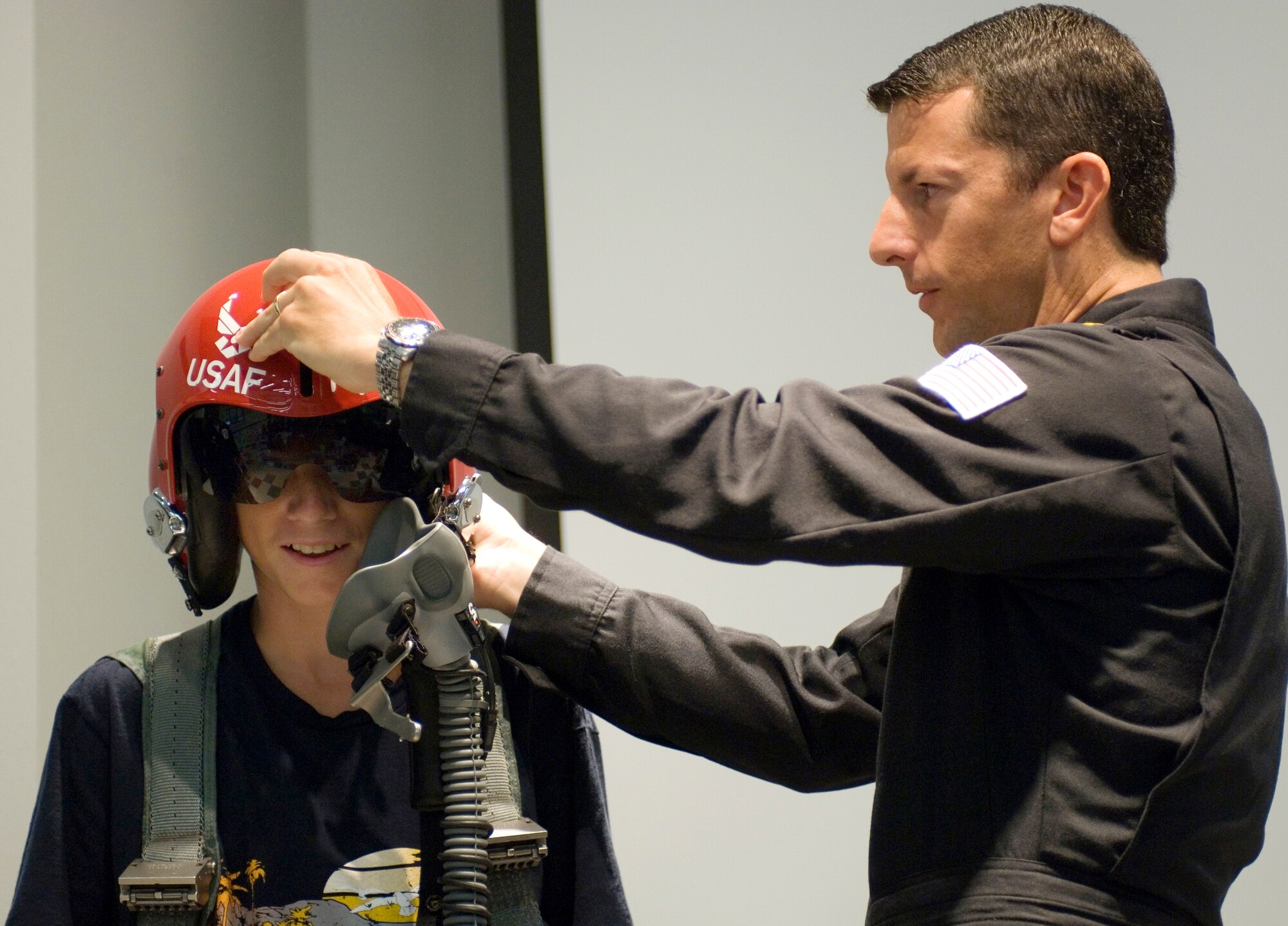 Maj. Brian Farrar of the Thunderbirds, the U.S. Air Force Air Demonstration Squadron, lowers the helmet visor for Colton Ceotto, who is attending a summer camp at Caty Cavins Community Center in O'Fallon, Ill., on Aug. 11. Major Farrar is Thunderbird No. 5 and lead solo for this year's team. The camp visit was part of Air Force Week community activities in the St. Louis area. (U.S. Air Force photo/Master Sgt. Jack Braden) 
