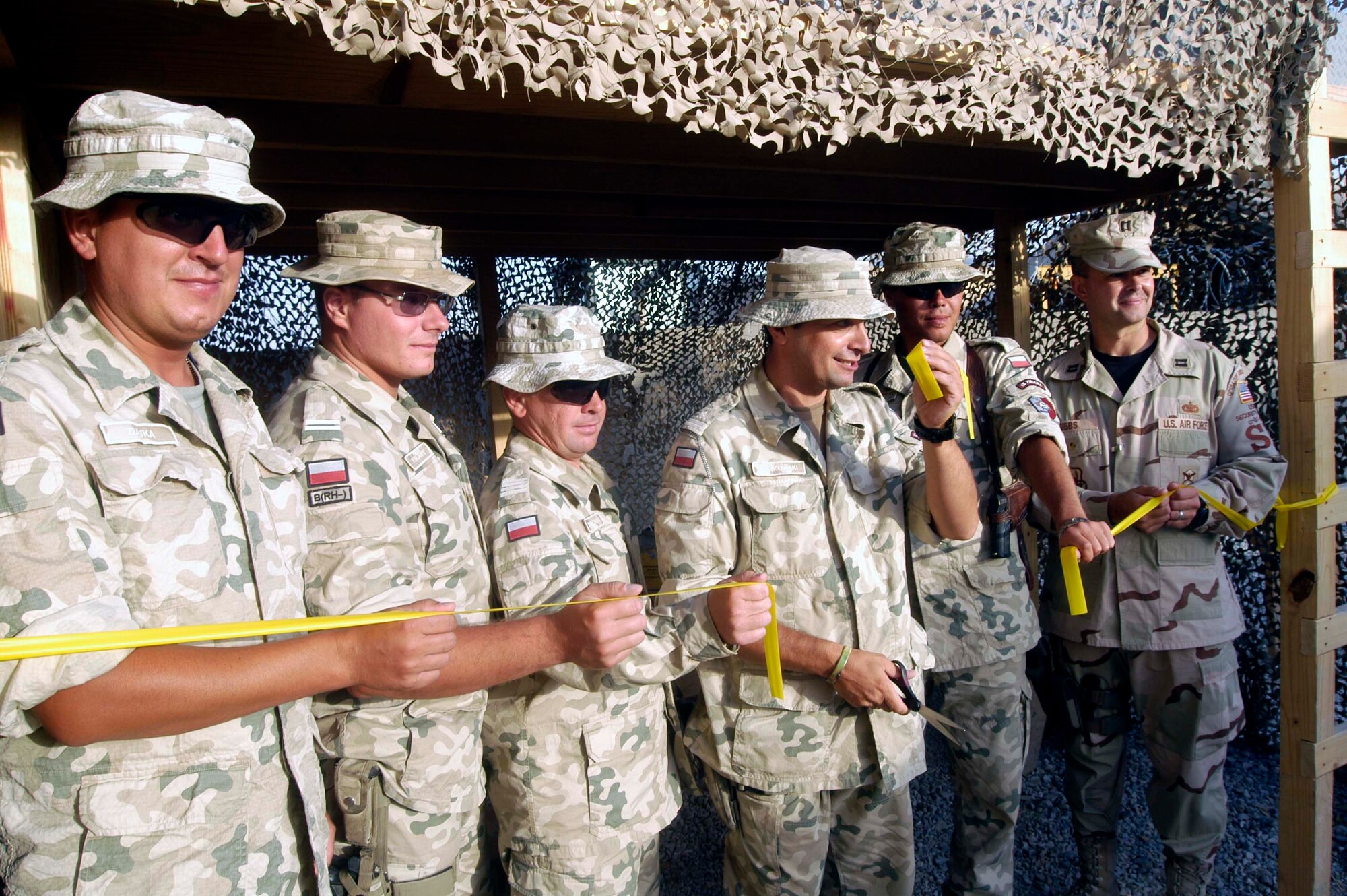 Maj. Jaroslaw Sulikowski, third from right, a construction officer from the Polish Army Expeditionary Construction Battalion,  holds up a piece of a ribbon during an impromptu ribbon cutting for a morale, welfare and recreation facility his team of engineers built for the U.S. Air Force's 455th Expeditionary Security Forces Squadron at Bagram Airfield, Afghanistan.  On the right, U.S. Air Force Capt. Michael Gibbs, 455th ESFS operations officer, is the American liaison to the team.  The team of engineers also built an entry control point for guest workers and are currently constructing a road on the Bagram flight line to enhance re-fueling of military aircraft.  The Polish Army is one of many international units represented at Bagram. (US Air Force photo/Maj. David Kurle)                           