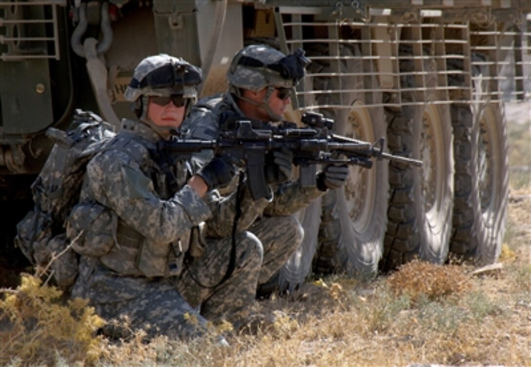 U.S. Army Spc. Jonh Littrell (left) and Pfc. Devin Gooch both with Mortar Platoon, 5th Battalion, 20th Infantry Regiment scan their sectors after dismounting a Stryker assault vehicle in the outskirts of Mosul, Iraq, on Aug. 6, 2006.  