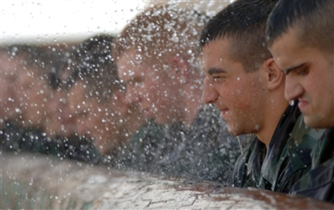 Cadres soak U.S. Air Force Airmen Kaufman, Whitehead and Culpepper along with 19 other pararescue trainees as they try to carry a heavy training log during the pararescue indoctrination-training course at Medina Base, Texas, on April 6, 2006.  