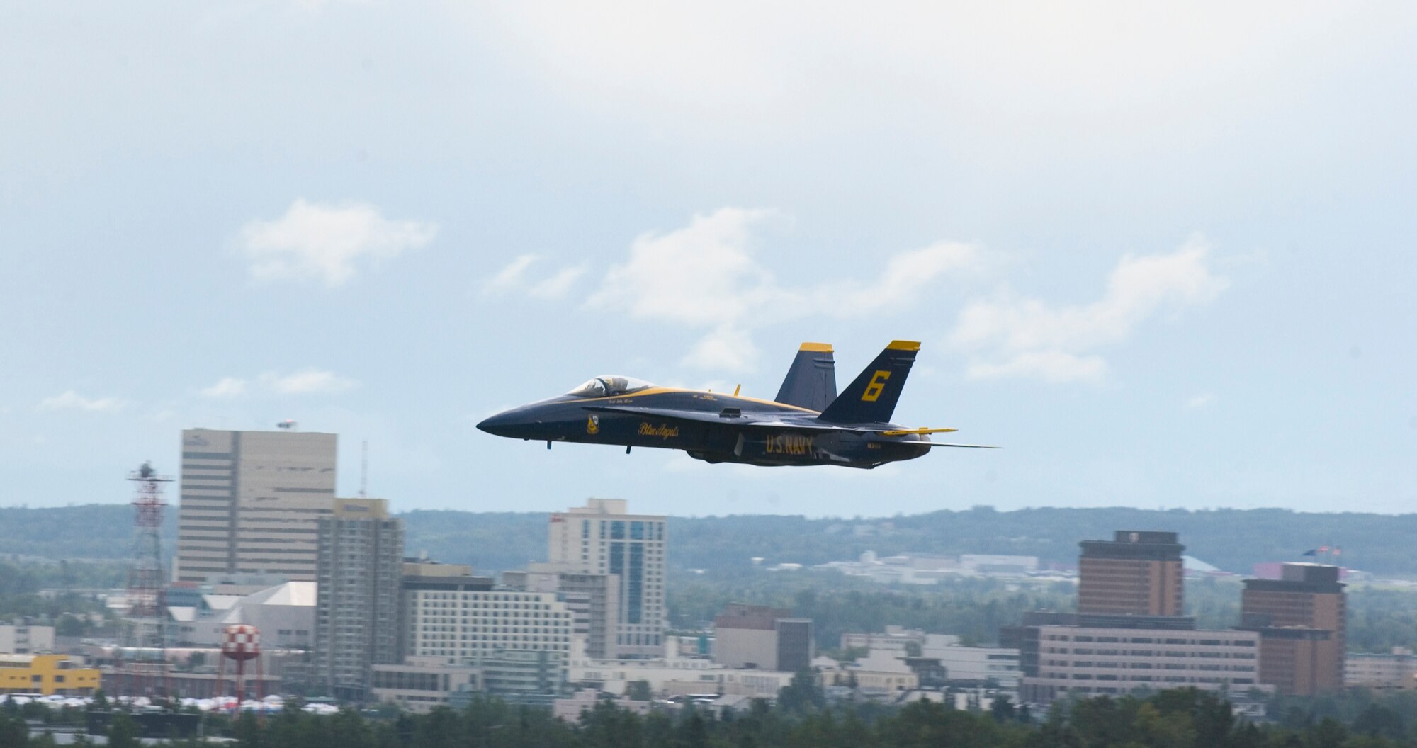 ELMENDORF AIR FORCE BASE, Alaska - An F-18 Super Hornet belonging to the Navy's Blue Angels speeds past the Anchorage skyline during Arctic Thunder 2006. Nearly 136,000 people attended Elmendorf's 60th air show and open house. The Blue Angels along with the Army's Golden Knights headlined the event. (U.S. Air Force photo by Senior Airman Garrett Hothan) 
