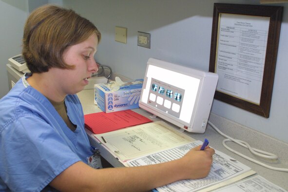 POPE AFB -- Senior Airman Carla Oltmer, 43rd Aeromedical Dental Squadron dental assistant, reviews a patient's charts and sets up his x-rays for the dentist. (U.S. Air Force photo/Senior Airman Stacia Zachary)