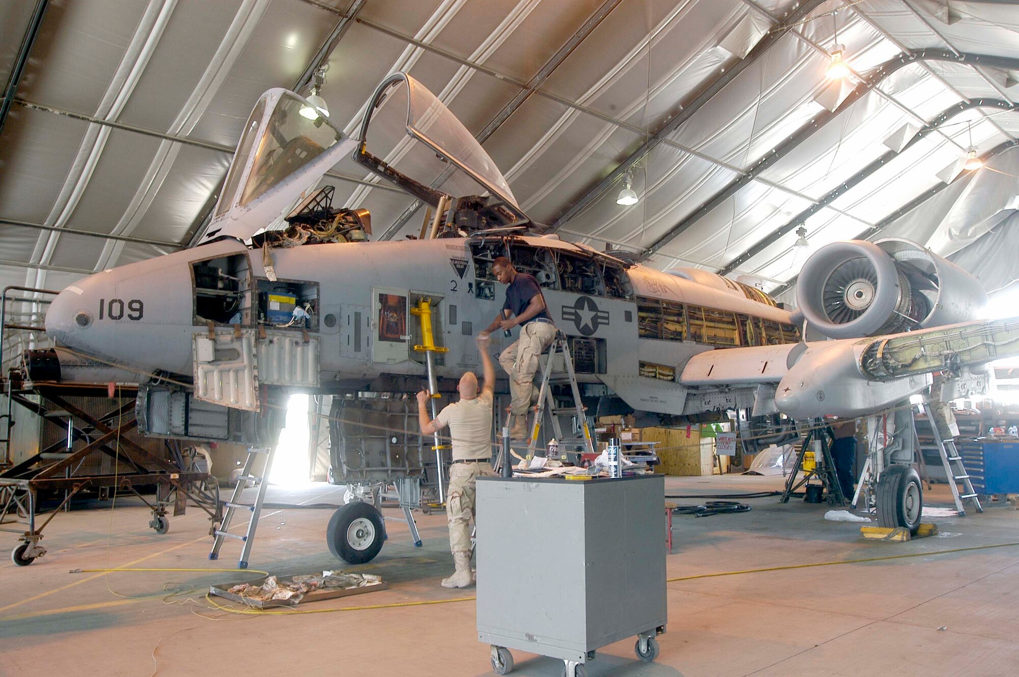 Staff Sgt. Shannon Hughes (left) hands Senior Airman Damon Johnson a tool as they work on an A-10 Thunderbolt II during its phase inspection at Bagram Air Base, Afghanistan. The Airmen are deployed from Spangdahlem Air Base, Germany, in support of Operation Enduring Freedom. The 455th Expeditionary Maintenance Group is working on the airplanes around the clock, to ensure consistent ability to meet the demand for the airframe in theater. (U.S. Air Force photo/Maj. David Kurle)