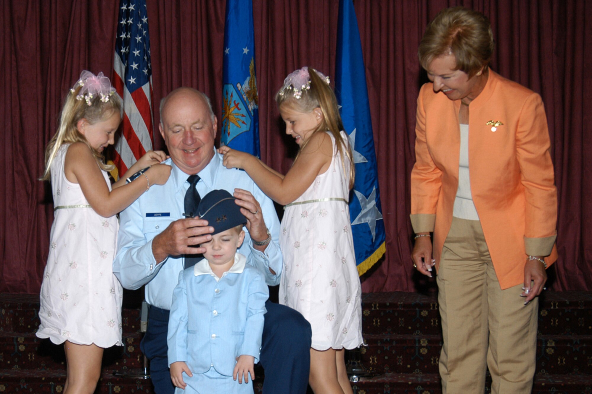 Megan (left) and Kaylee, granddaughters of Maj. Gen. Thomas Deppe, pin-on the general’s second star while his wife, Eileen looks on and grandson Rocco tries on the general’s flight cap at his promotion ceremony August 11. (Air Force photo by Bernie Ernst)