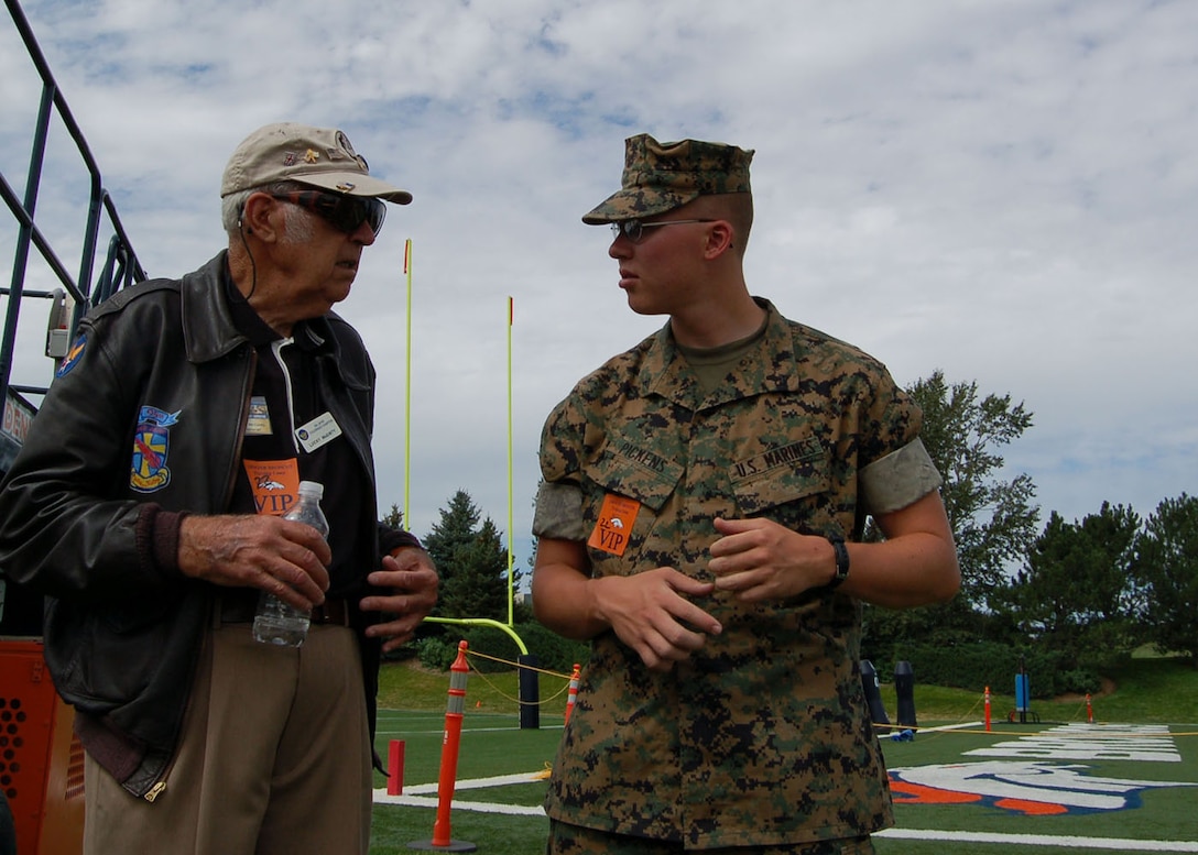 Lance Cpl. Christopher Pickens (right) talks with World War II veteran Lucky McGinty Aug. 9 at a Denver Broncos training camp practice. McGinty flew 29 combat missions into Germany as a B-17 gunner with the 95th Bomb Group. Pickens and thre other Marines were invited to the practice by the Greatest Generations Foundation to meet with World War II Veterans. Pickens is assigned to the Marine Cryptologic Support Battalion at Buckley Air Force Base in Colorado. The Greatest Generations Foundation is a non-profit educational organization that raises money to fully fund trips for veterans to revisit the sites of their former battlefields. (Photo by Air Force Staff Sgt. Aaron Cram)