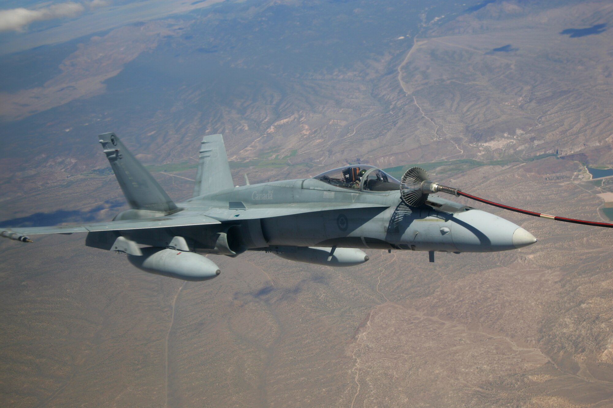A CF-18M from the 409th Tactical Fighter Squadron, Cold Lake, Canada, takes on fuel Aug. 15 from a CC-130T tanker, 17th Wing, 435th Squadron, Winnipeg, Canada. Canadian air forces are taking part in the first two-week period of exercise Red Flag, which ends 18 Aug. The CF-18s are performing air-to-ground strike operations during Red Flag, which pits friendly forces against Air Force Aggressor F-15s and F-16s over the 12,000-square-mile Nevada Test and Training Range Complex. (Photo courtesy Paul Ridgway, Typhire Photography)
