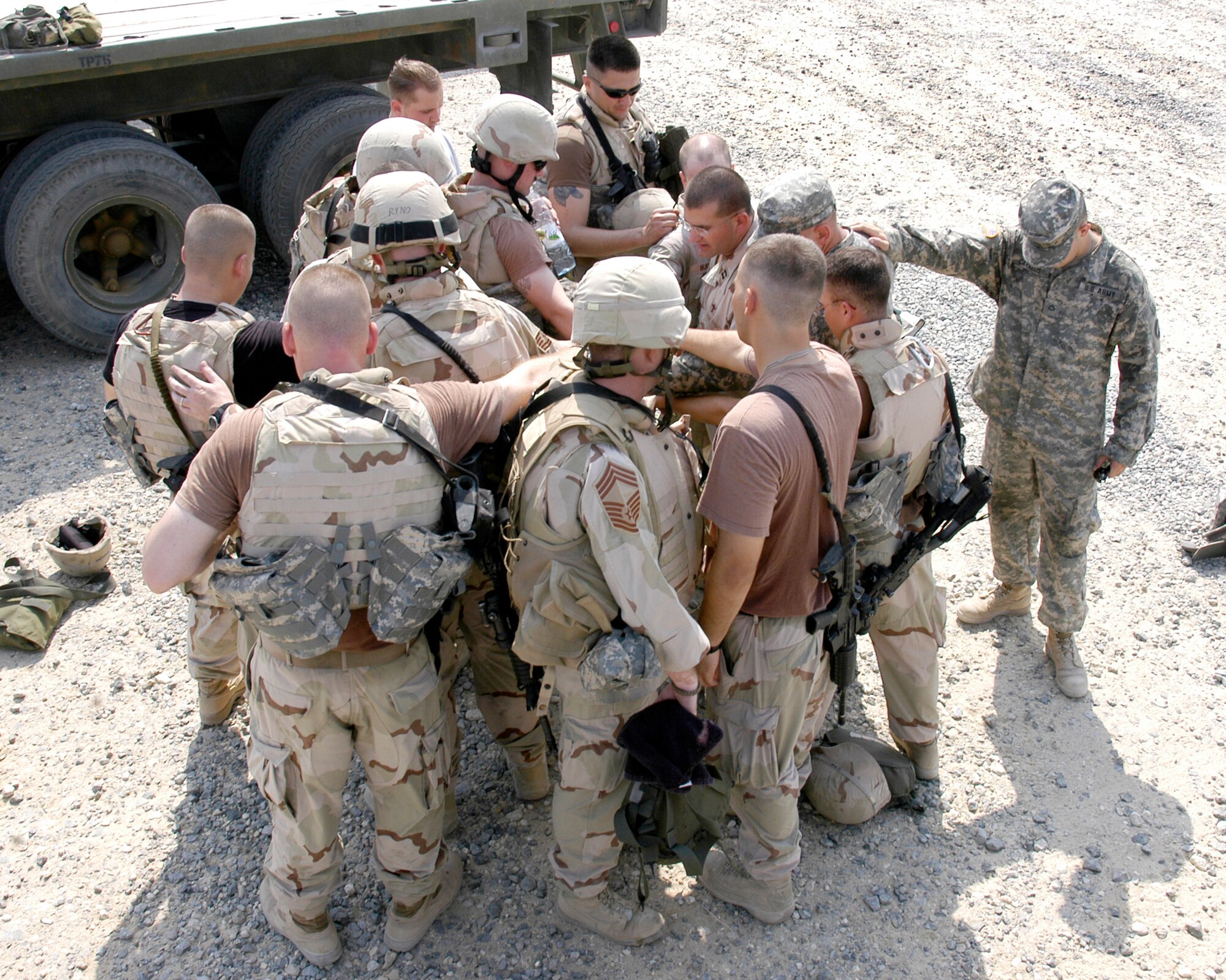 Airmen from the 424th Medium Truck Detachment and Soldiers from gun truck security command Charlie 1/12 gather for a prayer before heading out on a convoy. (U.S. Air Force photo/Maj. Tom Crosson)