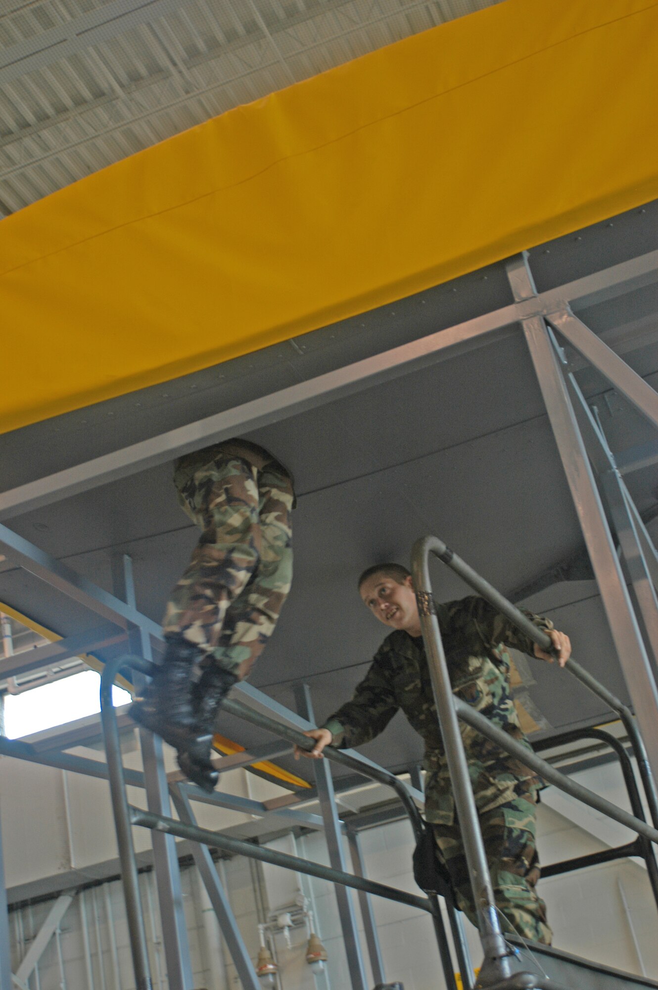 Senior Airman Henry Dungan, 6th Maintenance Squadron metals technologist, keeps an eye on safety as Senior Airman Dennis Emerson crawls into MacDill's new wing trainer. This full-size wing section can be used for confined spaces training for multiple specialties, and will allow maintenance  personnel from MacDill to deploy much faster.    