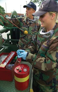 Staff Sgt. Tiffani Slaughter and Senior Airman Michael Leimbach, both fuels lab technicians with the 437th Logistics Readiness Squadron, take a fuel sample from a pump truck at the pumphouse Aug. 11. (U.S. Air Force photo/Airman 1st Class Sam Hymas)