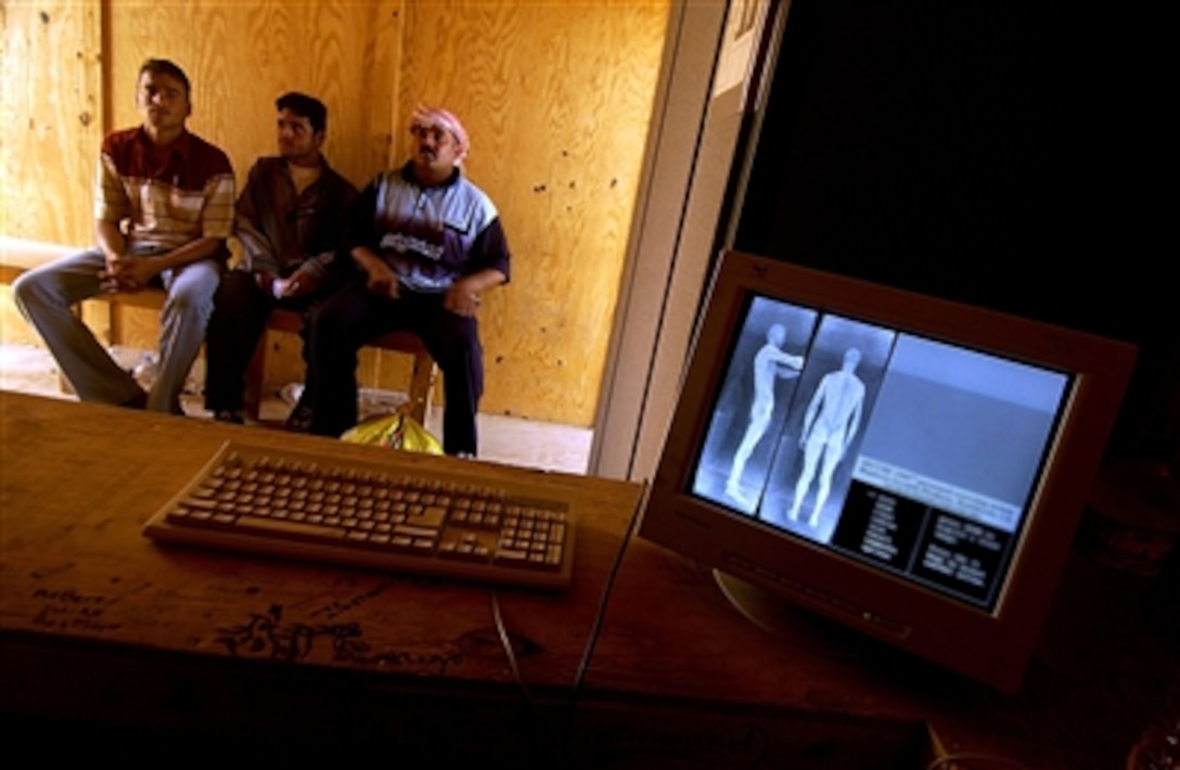 Iraqi men wait to be x-rayed for weapons during a recruiting event for the Iraqi police on Camp Blue Diamond in Ramadi, Iraq, Aug. 12, 2006. 